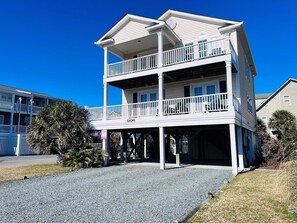 A two-story building with a balcony on the upper floor, a visible address number, and a gravel driveway. - - 2 the C - 4 Br Home (Supply)
