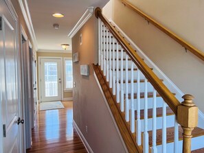 A hallway with a wooden staircase, a door, and a window. - - 2 the C - 4 Br Home (Supply)