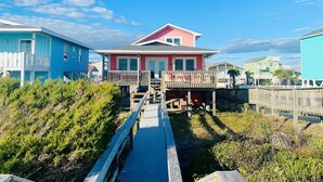 A coastal house with a wooden deck, a small porch, and a clear view of the ocean. - 3/4 Time - 4 Br Home (Supply)