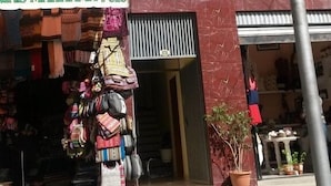 Un edificio con un letrero que dice "Residencial Alta Vista" y una tienda llamada "NITAS MARKAMA #828" con artículos coloridos exhibidos afuera.
