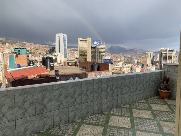 Un paisaje urbano con vista a montañas y un arcoíris.