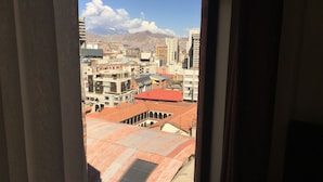 Vista desde una ventana con vista a un paisaje urbano, con edificios y montañas al fondo.