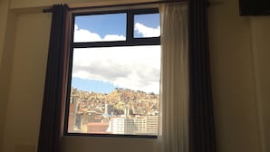 Una habitación con una ventana grande, cortinas y una cama.