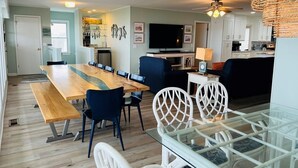 A modern kitchen with a dining area, a TV, and a ceiling fan.