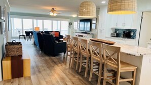 A modern kitchen with wooden bar stools, a dining table, and a large island.