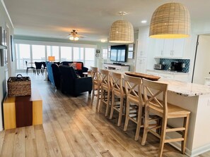 A modern kitchen with wooden bar stools, a dining table, and a large island.