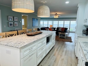A spacious kitchen with a large island, white cabinetry, and a view to the outside.