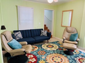 A living room with a sofa, two armchairs, a patterned rug, and a staircase in the background. - Beach Time 5 Bedroom Home by RedAwning (Supply)