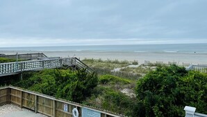 A beach view with a wooden deck and a sign indicating no swimming.