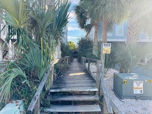A wooden staircase leading to a gated area with palm trees and a sign indicating no trespassing.
