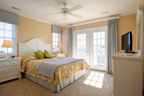 Une chambre à coucher comprenant un lit, des tables de chevet, un téléviseur et un ventilateur de plafond.