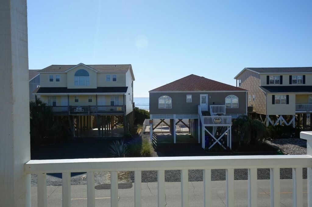 A beachfront hotel with multiple buildings, a covered walkway, and a view of the ocean.