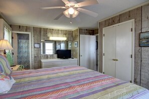 A bedroom with a bed, a ceiling fan, a dresser, a television, and a wardrobe.