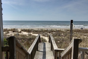 Eine Holztreppe führt zu einem Strand mit Blick auf das Meer.