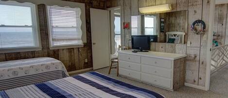Ein Schlafzimmer mit Bett, Kommode, Fernseher und Holzwänden.