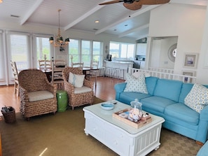 A spacious living area with wicker furniture, a blue sofa, and a white coffee table.