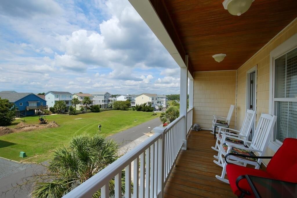 A porch with white railings and a view of a residential area.