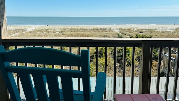 A wooden deck with a view of the beach.