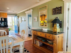 A kitchen with wooden cabinets, a dining table with chairs, a built-in bookshelf, and a large mirror.