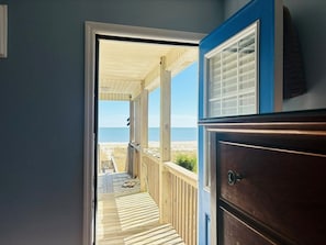 A doorway leading to a covered outdoor area with a view of the beach.
