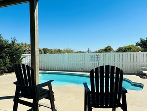 Ein Garten mit Schwimmbecken, zwei Adirondack-Stühlen und einem weißen Zaun.