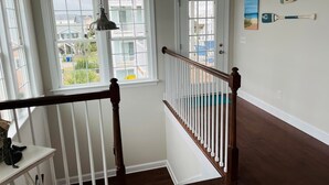 Una escalera con barandilla de madera y balaustres blancos, que conduce a una puerta con un ventanal arriba.
