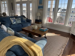 A living room with a blue sofa, a wooden coffee table, and a view of the outside through large windows. - Compass Rose 4 Bedroom Home by RedAwning (Supply)