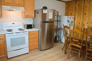 A kitchen with a stove, oven, refrigerator, and wooden chairs. - Do-little Dock 3 Bedroom Home by RedAwning (Supply)