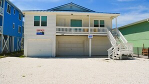 A two-story building with a garage, a balcony, and a staircase leading to the upper floor. - Do-little Dock 3 Bedroom Home by RedAwning (Supply)