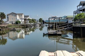 A calm waterway with docked boats, wooden walkways, and residential buildings. - Turtle Cove (formerly Fiddler's Green) 4 Bedroom Home by RedAwning (Supply)