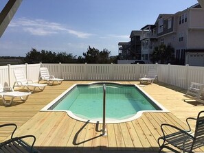 A wooden deck with a rectangular pool, lounge chairs, and a white fence. - Turtle Cove (formerly Fiddler's Green) 4 Bedroom Home by RedAwning (Supply)
