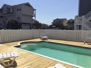 A swimming pool with a wooden deck, white lounge chairs, and a white fence. - Turtle Cove (formerly Fiddler's Green) 4 Bedroom Home by RedAwning (Supply)