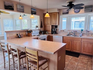 A kitchen with a central island, wooden cabinets, a stove, and a dishwasher.