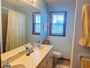 A bathroom with a double sink, a toilet, a window with blinds, and a towel rack. - Dry Dock - 4 Br Home (Supply)