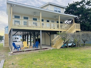 A two-story building with a covered patio area, outdoor seating, and a staircase leading to the upper level. - Dry Dock - 4 Br Home (Supply)