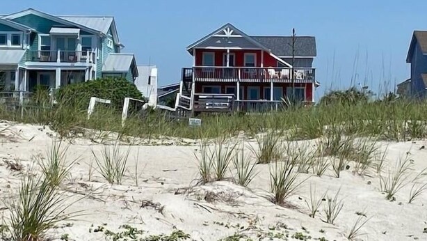 Une propriété située en bord de mer, avec un bâtiment à deux étages doté d’un balcon et d’une véranda couverte.