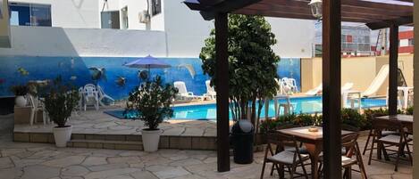 Een buitenzwembad, parasols bij het zwembad en ligstoelen