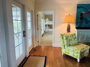 A hallway with wooden flooring, a green patterned chair, a lamp, and a painting on the wall. - Gray Goose 5 Bedroom Home by RedAwning (Supply)