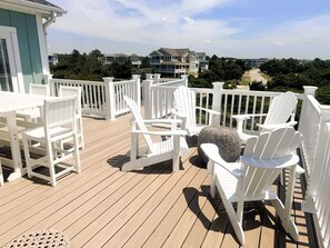 A wooden deck with white chairs and a round woven ottoman. - Dune Escape 5 Bedroom Home by RedAwning (Supply)