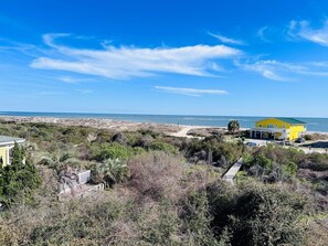 Ein Küstengebiet mit einem gelben Gebäude, einem Strand und blauem Himmel.