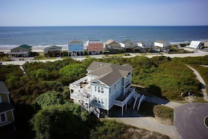 Uma propriedade costeira com várias casas, uma praia e vista clara para o oceano.