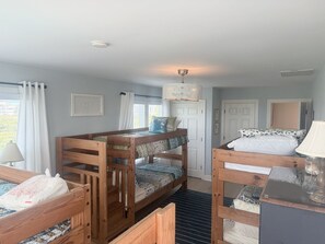 A room with bunk beds, a desk, a lamp, and a ceiling light fixture. - Dune Escape 5 Bedroom Home by RedAwning (Supply)