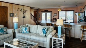 A living room with a sofa, coffee table, and a dining area with chairs and a table. - Great Place 5 Bedroom Home by RedAwning (Supply)