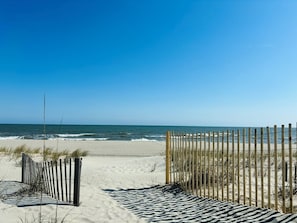 Ein Strand mit einer Holzlattenveranda und einer Streifenmatte, die zum Wasser führt.