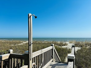 Een houten looppad dat naar een strand leidt, met een helder uitzicht op de oceaan.