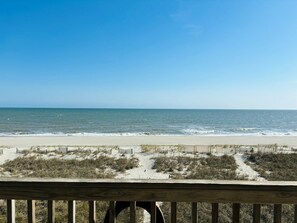 Blick auf einen Strand mit einer Holzterrasse und Sanddünen.