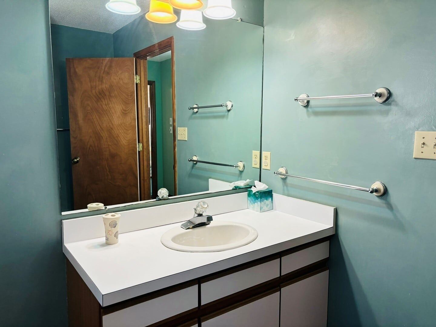 A bathroom with a white sink, a mirror, and a towel rack.