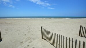 Una playa con una valla de madera y cielo despejado.