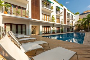 A modern hotel with a pool area, sun loungers, and a staircase leading to the upper floors. - Apartamento de Lujo Virrey de Eslava (Cartagena)