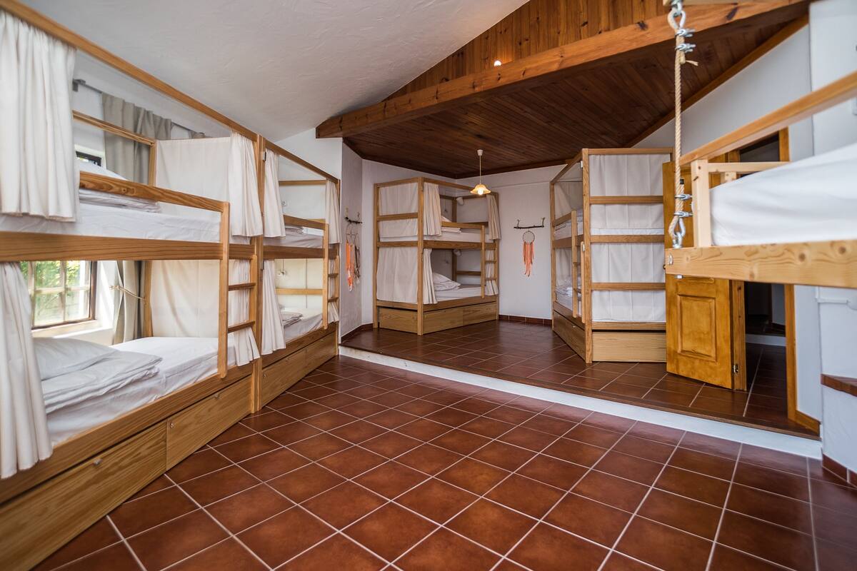 Un dormitorio con literas, vigas de madera y suelo de baldosas.